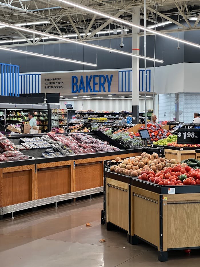 Modern grocery store produce section with fresh fruits and bakery signs.