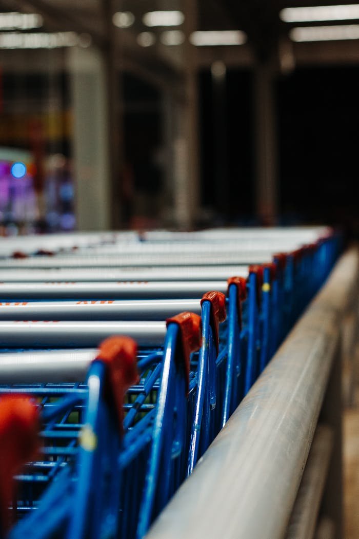 Line of blue shopping carts in a supermarket, focusing on retail shopping essentials.
